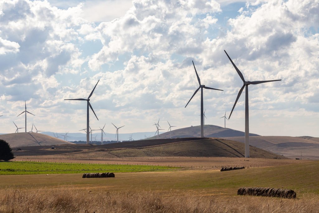 Wind turbines on green grass field under white clouds